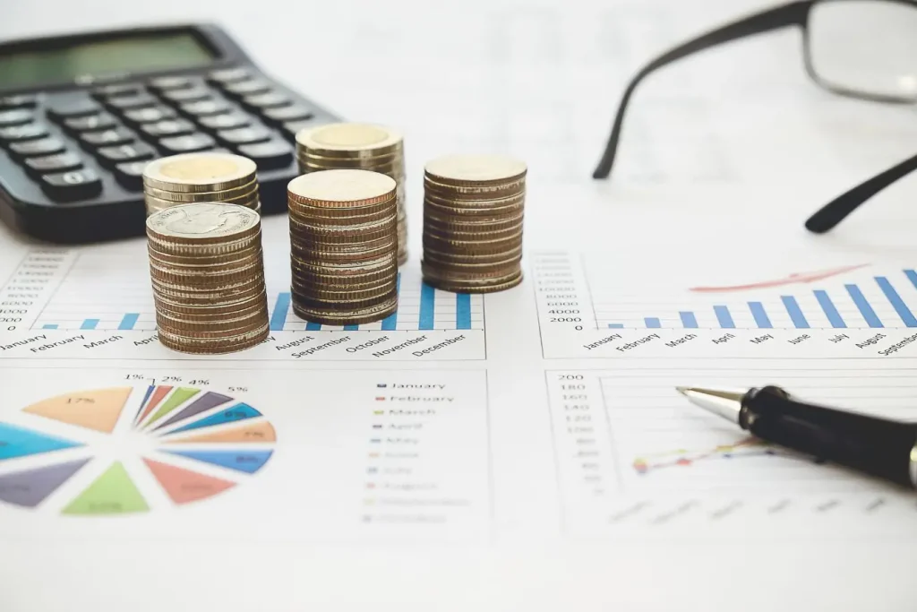 Piles de pièces posées sur graphiques financiers, symbole des pratiques pour calculer le seuil de rentabilité d’une entreprise.