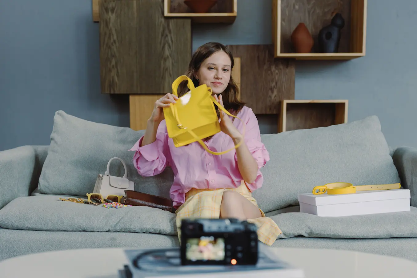 live shopping Personne assise sur canapé gris tenant sac jaune, symbole d’une démonstration de produits en direct dans un contexte de live shopping.