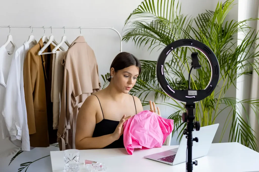 Gros plan sur chemise rose tenue devant objectif, image claire illustrant une session de live shopping mode.
