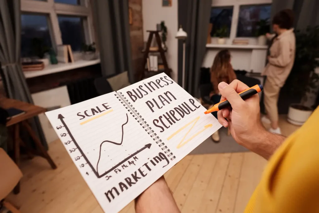 Personne tenant carnet avec schéma marketing et plan d’affaires, symbole d’une stratégie de marketing viral en préparation.