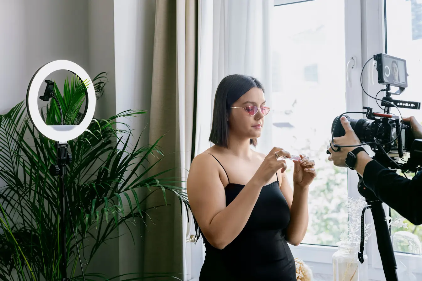 vidéo shoppable Personne en tenue noire filmée devant caméra et anneau lumineux, symbole d’une démonstration produit en vidéo shoppable.